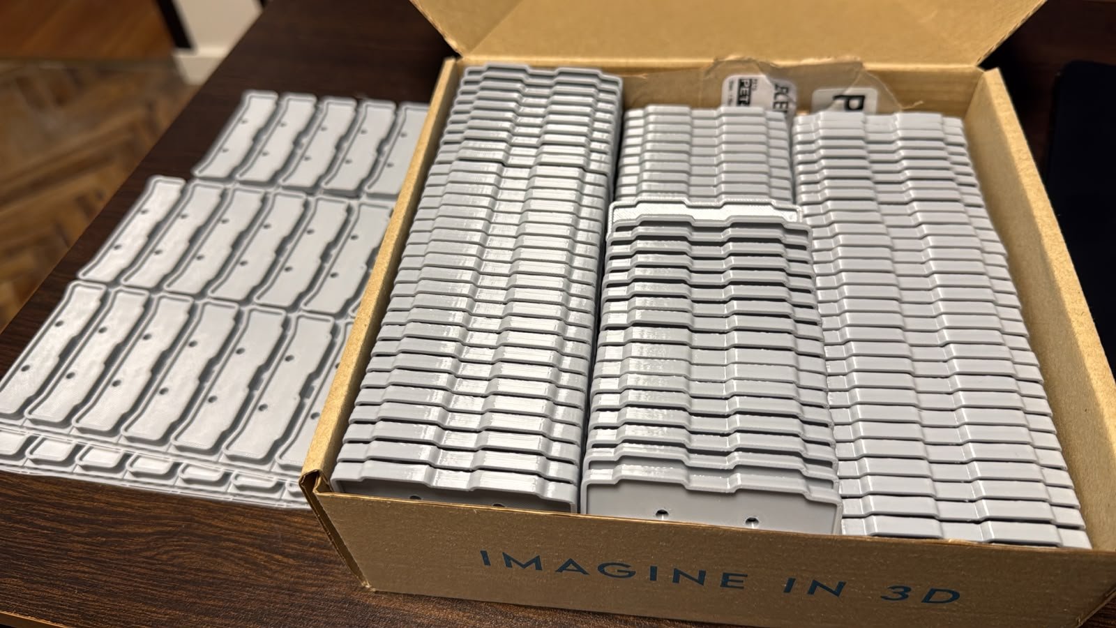 Lote de 400 tapas laterales en PETG gris para empresa de iluminación, apiladas en caja